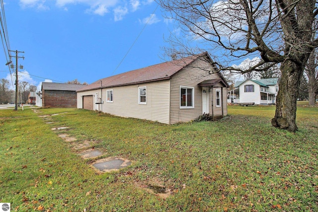 view of side of home with a garage, a yard, and an outdoor structure