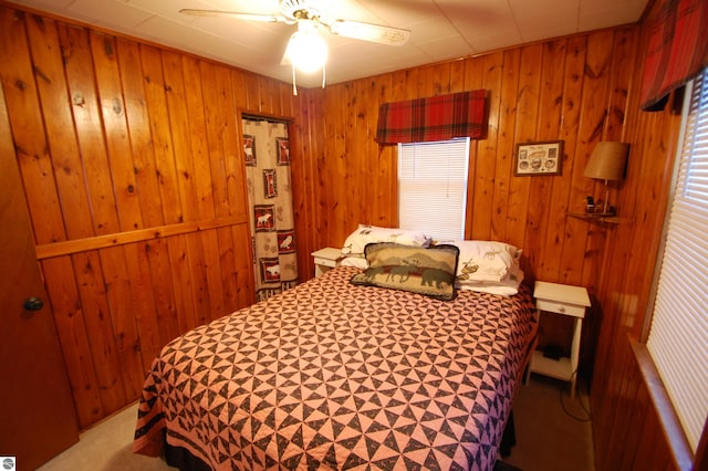 bedroom with wood walls, ceiling fan, and light colored carpet