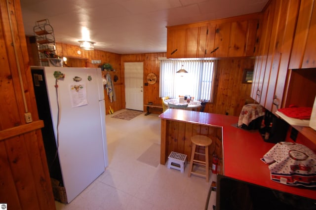 kitchen with white refrigerator and wooden walls