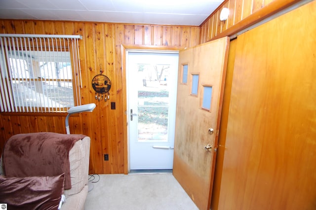 doorway to outside featuring wood walls and light carpet