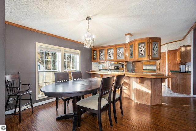 dining area with dark wood-type flooring, ornamental molding, a textured ceiling, and a notable chandelier