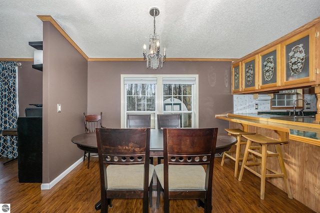 dining room with crown molding, a textured ceiling, a notable chandelier, dark hardwood / wood-style floors, and sink