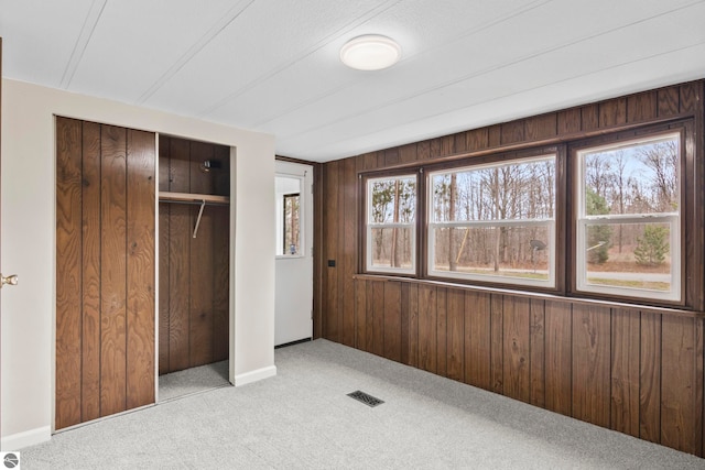 unfurnished bedroom with a closet, multiple windows, and wood walls