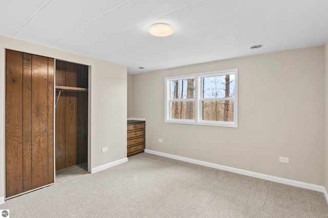 unfurnished bedroom with light carpet and a closet