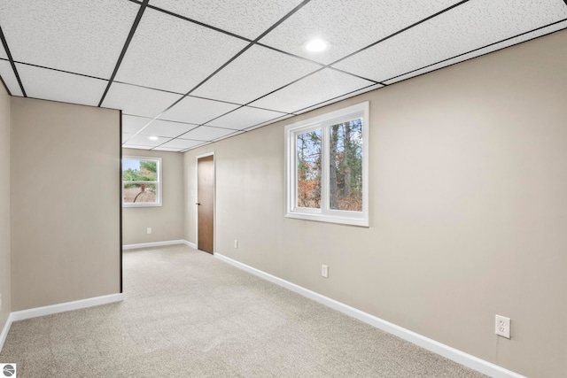 basement with light colored carpet and a paneled ceiling