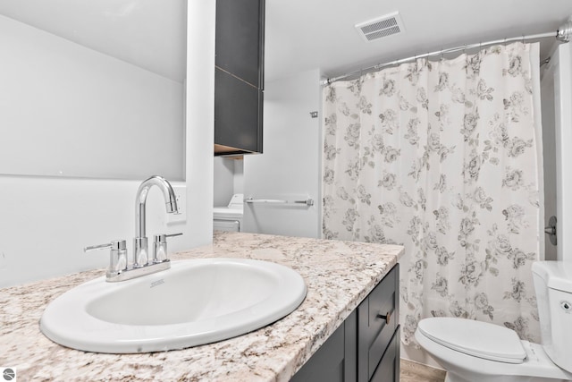 bathroom with curtained shower, vanity, and toilet