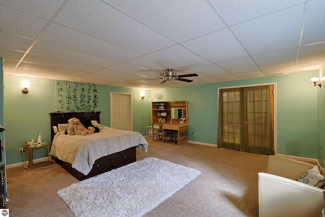 carpeted bedroom with a paneled ceiling and ceiling fan