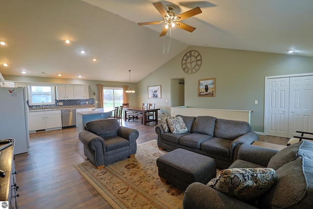 living room with high vaulted ceiling, sink, hardwood / wood-style floors, and ceiling fan with notable chandelier