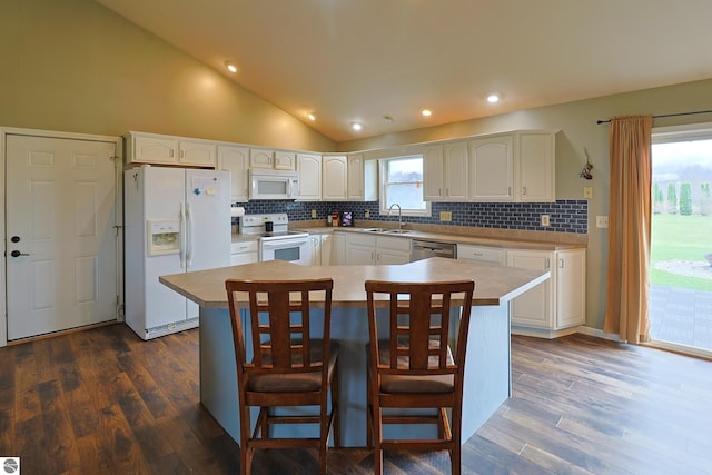 kitchen with sink, dark hardwood / wood-style floors, a kitchen island, white cabinetry, and white appliances