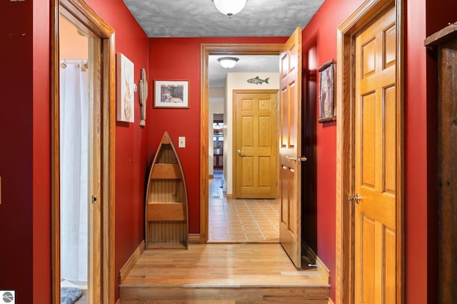 hall featuring a textured ceiling and light hardwood / wood-style floors