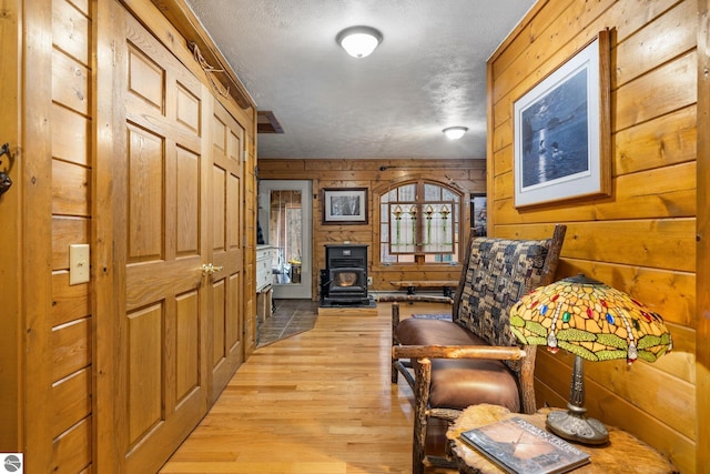 hall featuring wood walls, a textured ceiling, and light hardwood / wood-style flooring