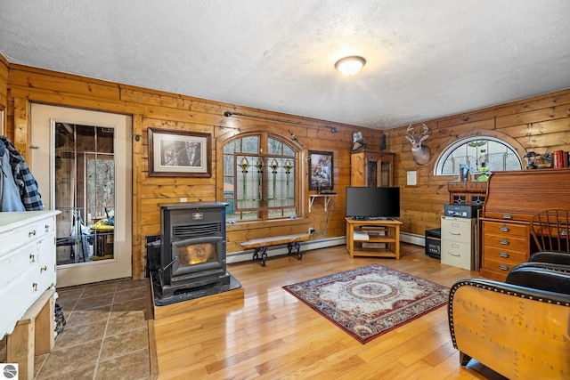 living room with baseboard heating, hardwood / wood-style floors, a textured ceiling, and a wood stove