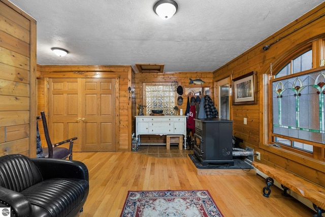 interior space with wooden walls, a wood stove, and light hardwood / wood-style floors