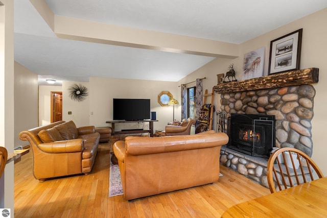 living room featuring hardwood / wood-style flooring, a stone fireplace, and lofted ceiling