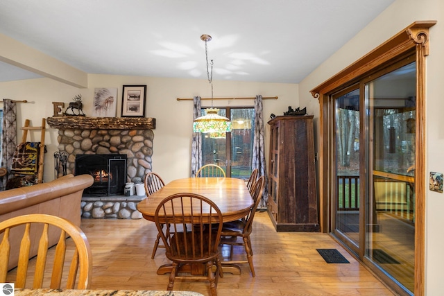 dining space featuring a stone fireplace, light hardwood / wood-style floors, and vaulted ceiling