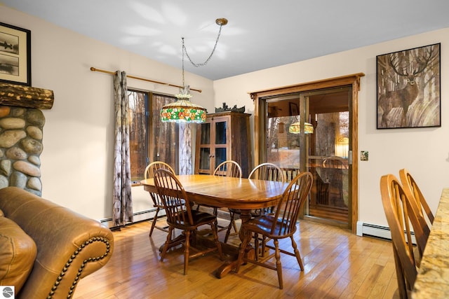 dining space with a baseboard heating unit, a wealth of natural light, and light hardwood / wood-style flooring