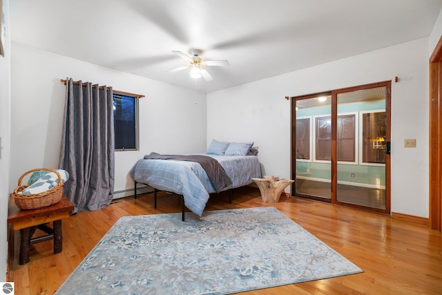 bedroom with a baseboard heating unit, hardwood / wood-style floors, and ceiling fan