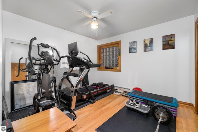 exercise area featuring hardwood / wood-style flooring, ceiling fan, and a baseboard heating unit