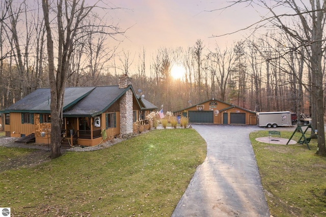 view of front of property with a garage, a yard, and an outdoor structure