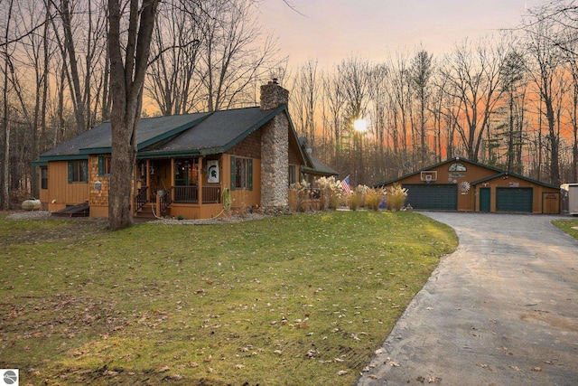 view of front of home with an outbuilding, covered porch, a garage, and a yard