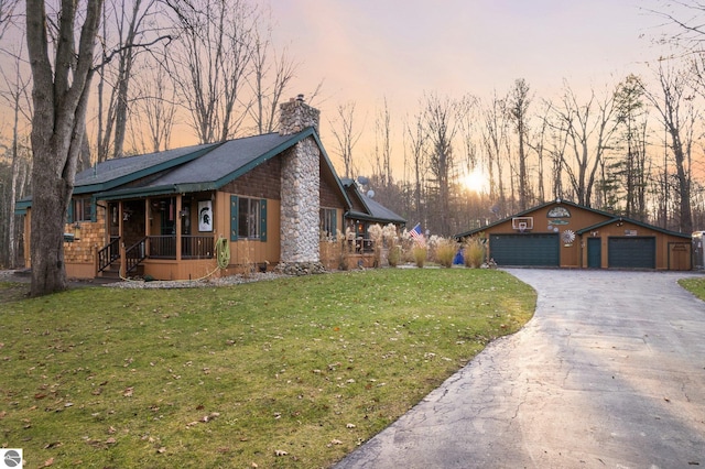 ranch-style house featuring an outbuilding, a garage, a porch, and a lawn