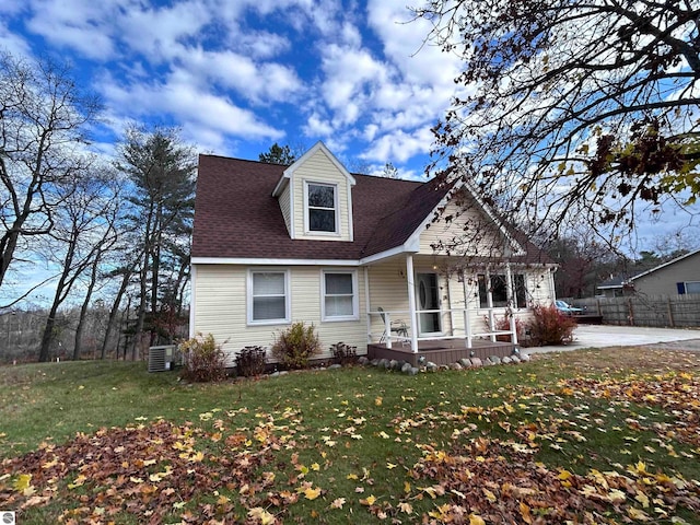 view of front of home featuring central AC unit, a porch, and a front yard