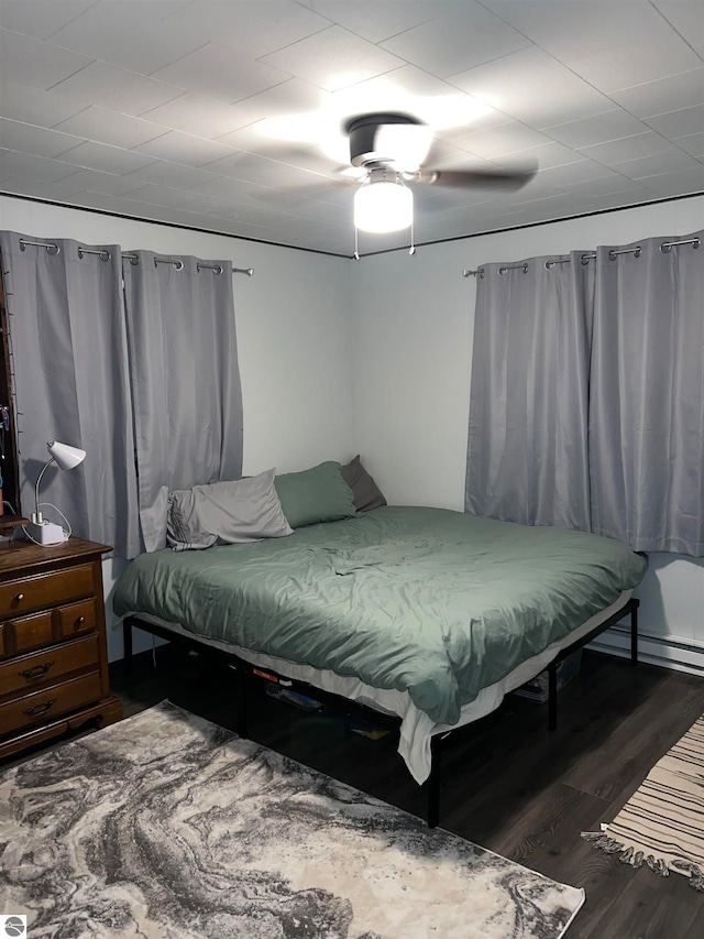 bedroom with dark wood-type flooring, ceiling fan, and baseboard heating