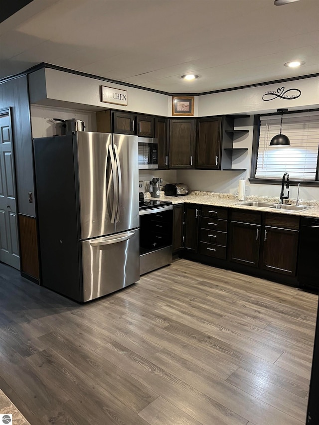 kitchen featuring pendant lighting, appliances with stainless steel finishes, wood-type flooring, and sink