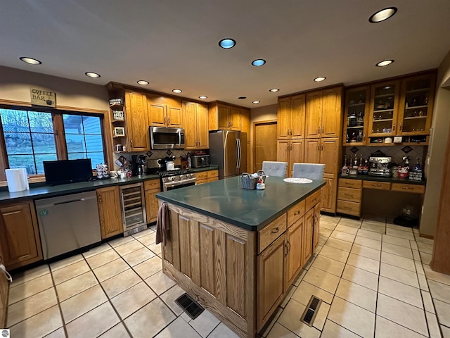 kitchen featuring a center island, beverage cooler, light tile patterned flooring, backsplash, and appliances with stainless steel finishes