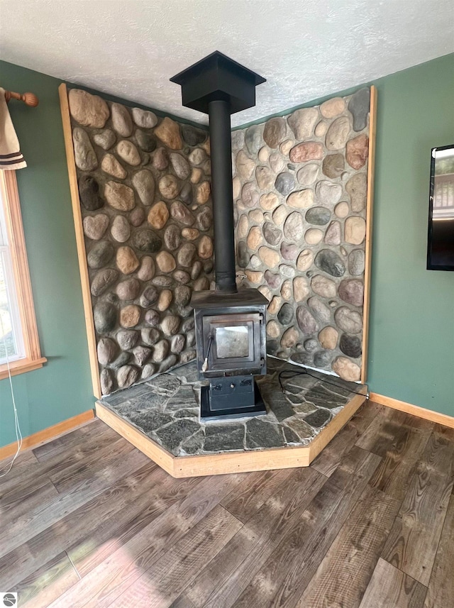 room details with hardwood / wood-style floors, a textured ceiling, and a wood stove