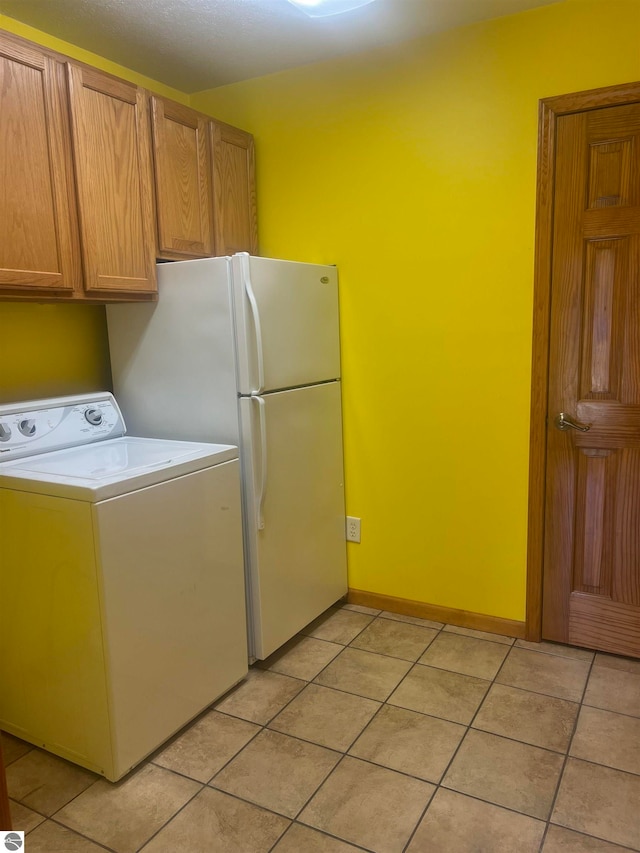 laundry area featuring washer / clothes dryer, light tile patterned floors, and cabinets