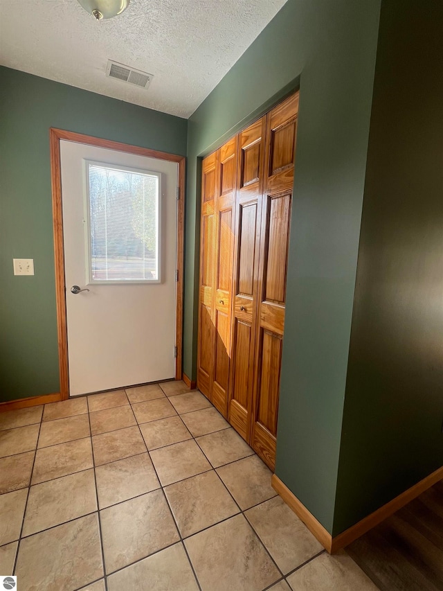 doorway with light tile patterned flooring and a textured ceiling