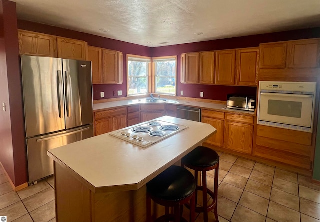 kitchen featuring a center island, light tile patterned floors, a breakfast bar area, and appliances with stainless steel finishes