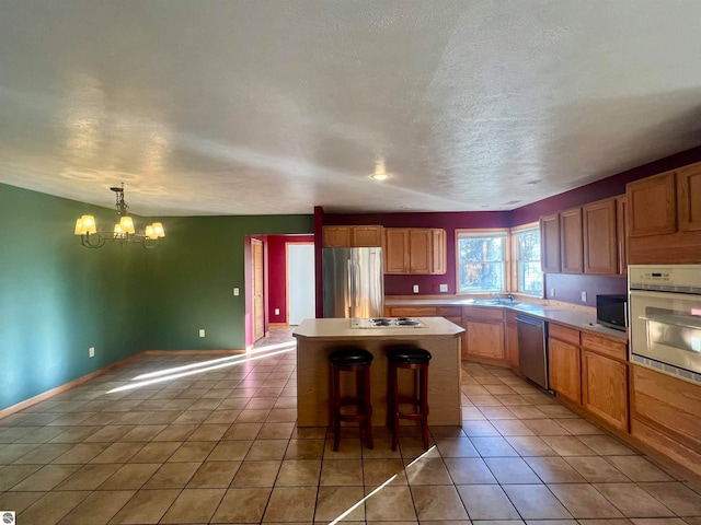 kitchen featuring an inviting chandelier, a kitchen breakfast bar, hanging light fixtures, a kitchen island, and stainless steel appliances