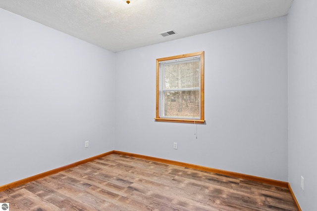 empty room with a textured ceiling and hardwood / wood-style flooring