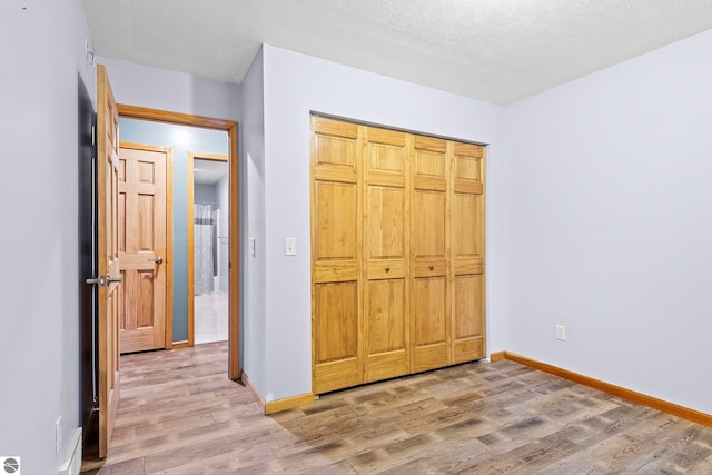 unfurnished bedroom featuring a closet, a textured ceiling, and hardwood / wood-style flooring