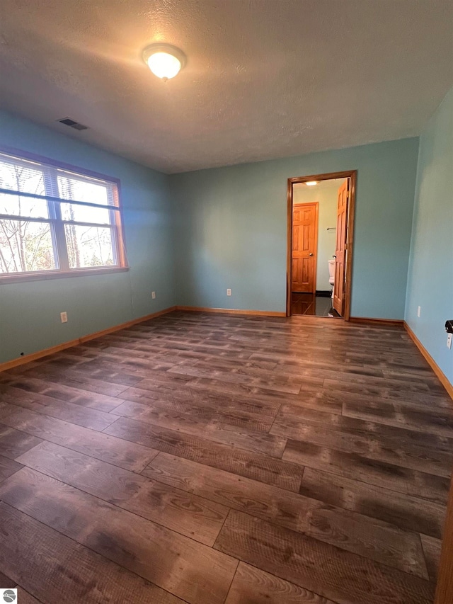 empty room with a textured ceiling and dark wood-type flooring