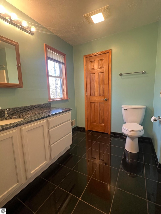 bathroom with tile patterned flooring, vanity, a textured ceiling, and toilet