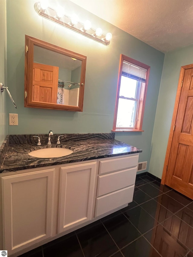 bathroom with a textured ceiling, vanity, and tile patterned floors