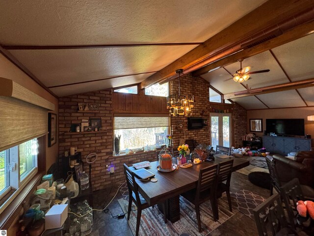 dining area with a textured ceiling, ceiling fan with notable chandelier, vaulted ceiling with beams, and brick wall