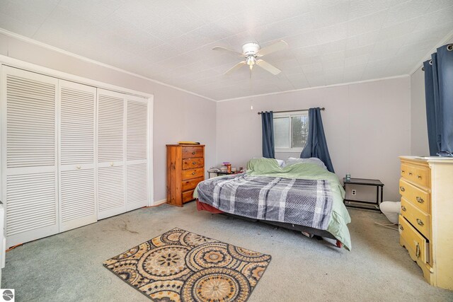 carpeted bedroom with ceiling fan, a closet, and ornamental molding