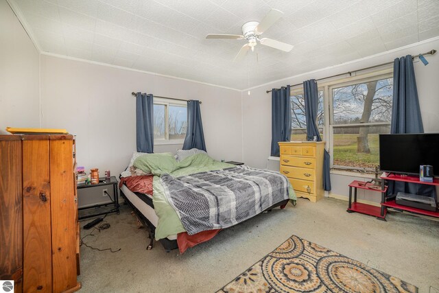 carpeted bedroom featuring ceiling fan and crown molding