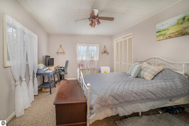 carpeted bedroom with ceiling fan, a closet, and ornamental molding