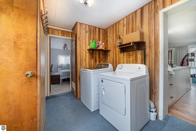 laundry area with wood walls, dark wood-type flooring, and washer and dryer