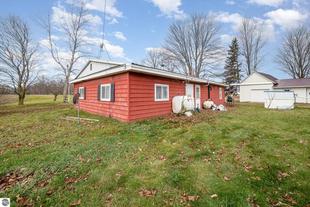 exterior space with a garage, a lawn, and an outbuilding