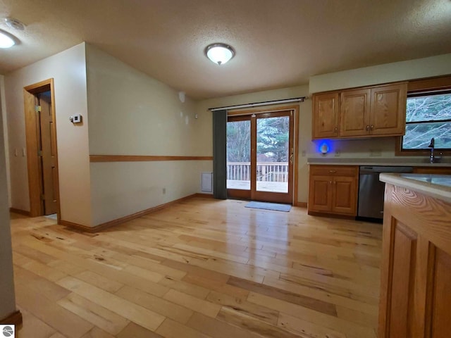 kitchen featuring stainless steel dishwasher, a textured ceiling, and light hardwood / wood-style floors