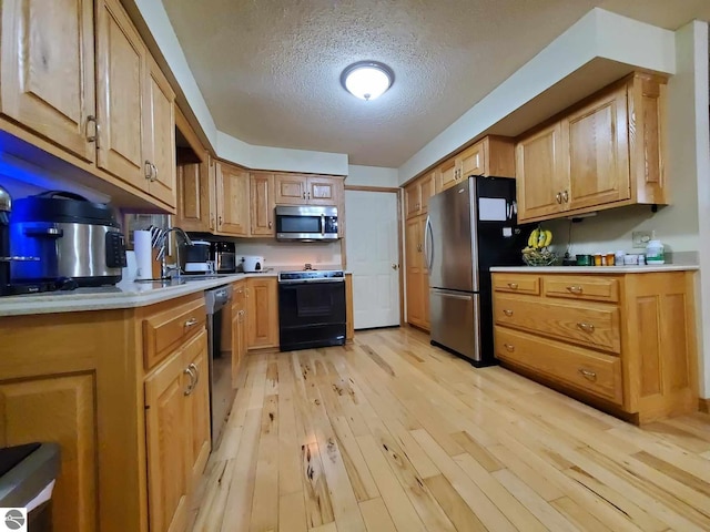 kitchen with sink, light wood-type flooring, a textured ceiling, and appliances with stainless steel finishes