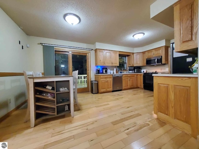 kitchen featuring a textured ceiling, stainless steel appliances, and light hardwood / wood-style floors