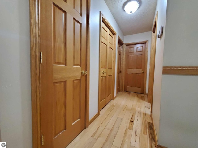 hall featuring light hardwood / wood-style flooring and a textured ceiling