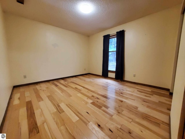 empty room featuring a textured ceiling and light hardwood / wood-style flooring